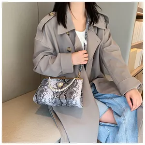 Sac à main chic imprimé serpent avec poignée en perles élégante, porté dans un style de rue