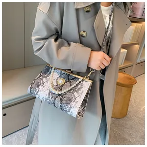Détail du sac à main motif serpent avec poignée en perles et fermoir en métal doré chic