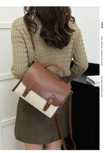 Detail of vintage messenger bag featuring brown leather flap and cream canvas stitching