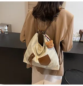Detail of canvas tote with brown leather straps and a cute plush bear charm accessory