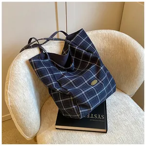 Detailed macro view of a blue checkered canvas tote bag featuring an oval gold logo plaque