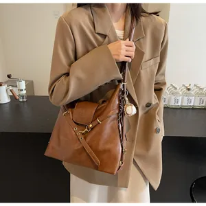 Primer plano detallado del bolso tote marrón vintage con hebillas metálicas y colgante