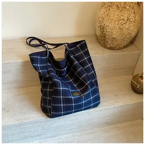 Close-up of a blue and white grid pattern tote bag placed on stone stairs