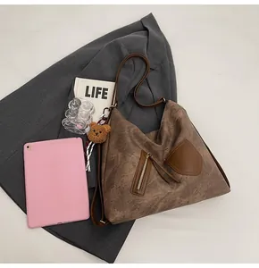Brown vintage large tote bag with zipper details and a plush bear charm on a suit