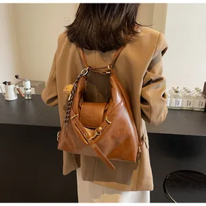 Detalle de una mochila de cuero suave color caramelo en una modelo en oficina moderna