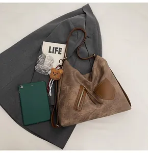 Detailed close-up of brown vintage tote bag with metal zipper and plush bear charm