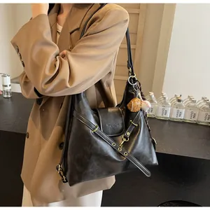 Detalle de un bolso tote de cuero negro con marca de moda y dijes deportivos creativos