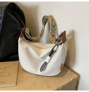Detail der weißen Halbmond-Tasche mit ethnischem breitem Gurt und Quasten-Reißverschluss