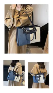 Detalle del bolso tote de lona bicolor con ribetes azul marino y herrajes dorados