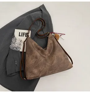 Detailed close-up of dark brown vintage hobo bag with textured leather and plush charm