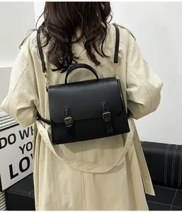Rear view of model wearing a vintage black satchel backpack with gold metal hardware