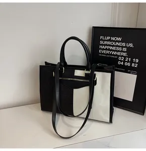 Detalle del bolso tote minimalista en tela de contraste blanco y negro con bolsillo con cremallera
