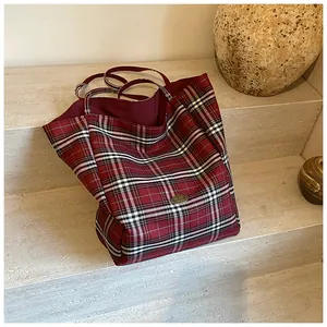 Close-up of red plaid canvas tote bag with handmade metal plate on stone stairs