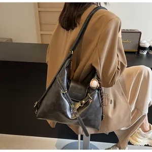 Detalle del bolso bandolera de cuero negro con costuras blancas y charm de béisbol