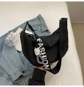 Detail der schwarzen Halbmondtasche mit breitem Schultergurt und FASHION-Schriftzug