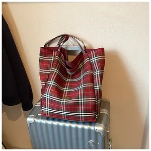 Detail of red and black tartan tote bag with handmade label on silver suitcase