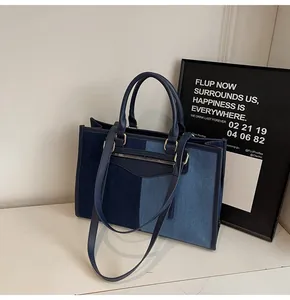 Detalle de bolso tote de mezclilla patchwork azul con asas y borlas decorativas