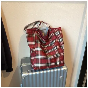 Close-up of red plaid tote bag featuring classic Scottish pattern on a metal suitcase