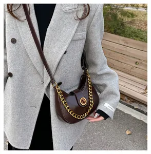 Detail view of deep coffee semi-moon shoulder bag with golden clasp and chain accent