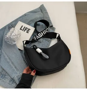 Detail der schwarzen Halbmond-Stofftasche mit breitem 'FASHION'-Gurt und geflochtenem Zipper