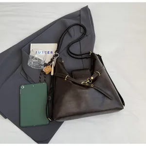 Bolso hobo marrón oscuro de cuero mate con hebilla dorada sobre sábanas blancas