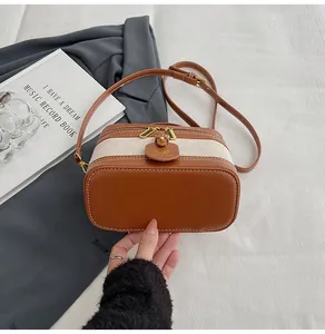 Dettaglio borsa a tracolla vintage in pelle marrone e tela con finiture dorate