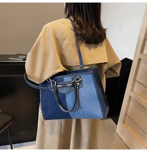 Detalle del bolso tote de mezclilla patchwork con asas de cuero y correa para el hombro