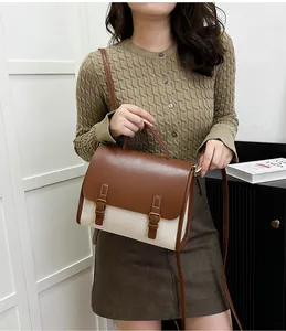 Detail of vintage messenger bag in brown leather and cream canvas with gold buckles
