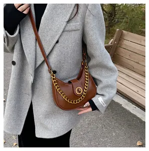 Detail of caramel brown moon-shaped shoulder bag with gold metal buckle and chain strap