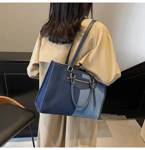 Detalle de bolso tote de lona en patchwork azul con asas de cuero y bolsillo de cremallera
