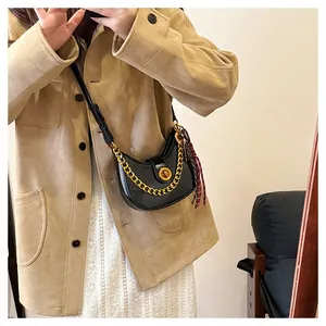 Detail of black crescent shoulder bag with golden chain strap and plaid silk scarf
