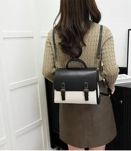 Detail view of vintage-style two-tone messenger bag worn on shoulders in an indoor setting