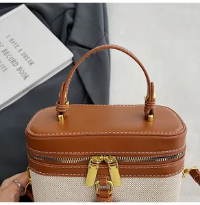 Dettaglio borsa squadrata bicolore con cuciture a contrasto e finiture dorate