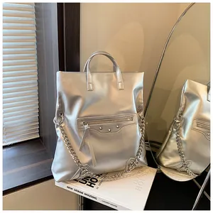 Detail of silver metallic tote bag with chain strap, studs, and tassel zipper details