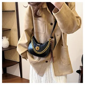 Detail of black crescent shoulder bag with chunky gold chain and turn-lock closure