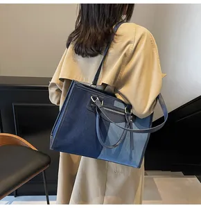 Detalle del bolso tote de retazos de mezclilla con correa ajustable llevado por modelo