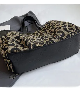 Détail du tissage imprimé léopard et du cuir grainé noir sur un sac cabas