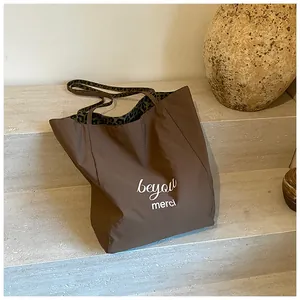 Close-up of stylish leopard print shoulder straps and printed lettering on a brown tote bag