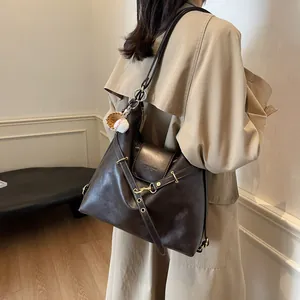 Bolso tote de cuero marrón con texto en relieve y colgante de béisbol en una modelo