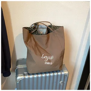 Detail of coffee nylon tote bag with leopard print lining on a silver suitcase