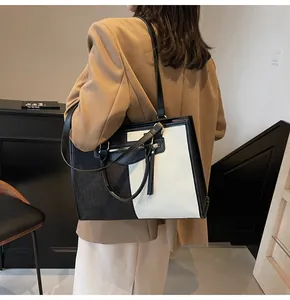 Detalle de un bolso tote en blanco y negro con correas ajustables y cierre de cremallera