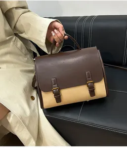 Brown leather and beige canvas vintage messenger bag held by a model on a leather sofa