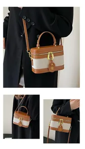 Dettagli di una borsa a scatola in pelle marrone e tela beige con hardware dorato e logo