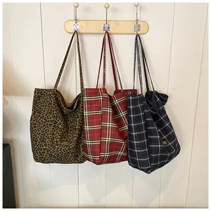 Detailed view of large tote bags in leopard print and plaid patterns on wall hooks