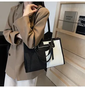 Detalle del bolso tote de lona bicolor blanco y negro con cremallera y borla larga
