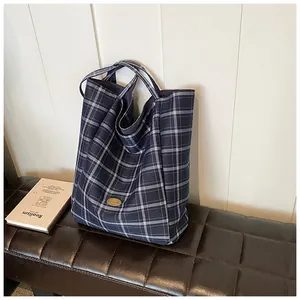 Close-up of classic blue checkered tote bag featuring a gold oval metallic decorative emblem