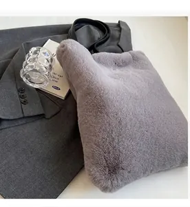 Détail d'un sac seau en peluche grise avec bandoulière en cuir noir et texture en fausse fourrure
