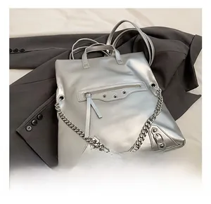 Detail view of metallic silver handbag with biker-style studs and decorative chains