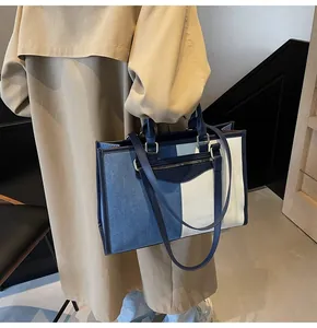 Detalle de un bolso tote de lona bicolor con paneles de contraste azul marino y crema