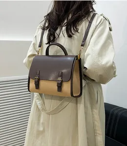 Classic two-tone messenger bag with brown leather flap and beige canvas on trench coat